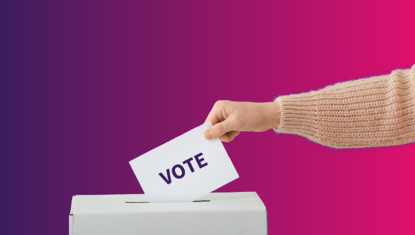 Hand placing a voting ballot into a box